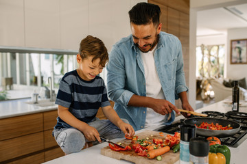 father and son preparing food in kitchen