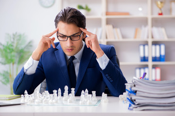 Young businessman playing glass chess in office