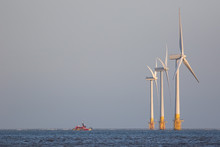 Offshore Wind Farm Turbines On Sea Horizon With Maintenance Boat