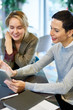 © Seventyfour - Portrait of successful businesswoman smiling happily while talking to young female colleague and using digital tablet during business meeting in office