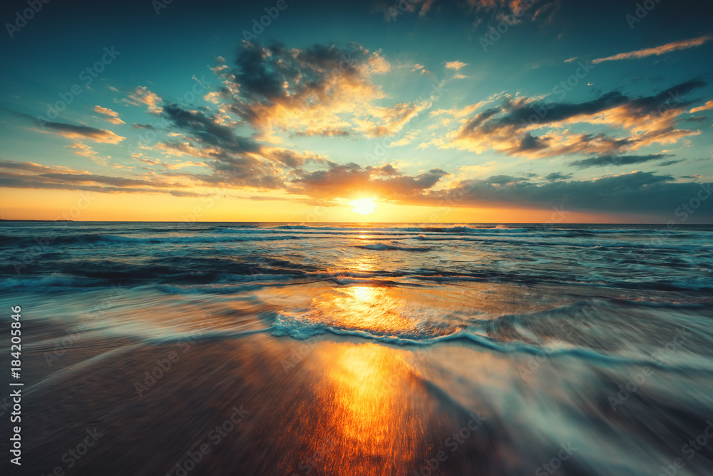 Obraz Piękny wschód słońca nad morzem z rozmytymi falami fototapeta, plakat