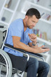 © auremar - disabled man in wheelchair using digital tablet at home