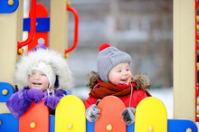 Little Boy And Girl In Winter Clothes Having Fun In Outdoors Playground