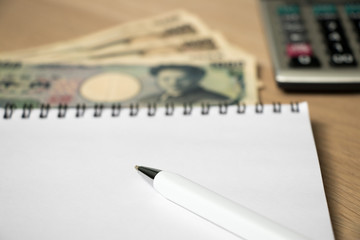 Poster - Blank note book with pen, japanese yen and calculator on wood table background