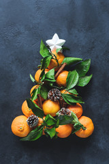 Christmas tree with tangerines, spices and pine cones decorated with white star. Top view, toned image. Traditional Christmas background