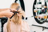 cropped image of hairdresser trimming ends of hair in salon