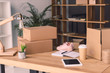 © LIGHTFIELD STUDIOS - freelance worker workplace with cardboard boxes, notebook and pair of shoes at home office