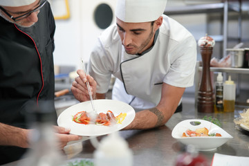 Professional cook chefs in kitchen improving dish composition