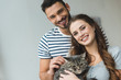 © LIGHTFIELD STUDIOS - smiling young couple holding cat in hands and looking at camera