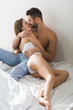 © LIGHTFIELD STUDIOS - happy young couple embracing and kissing in bed in morning