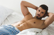 © LIGHTFIELD STUDIOS - shirtless young man in pajamas pants lying in bed
