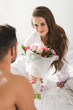 © LIGHTFIELD STUDIOS - man presenting beautiful bouquet to girlfriend in morning in bed