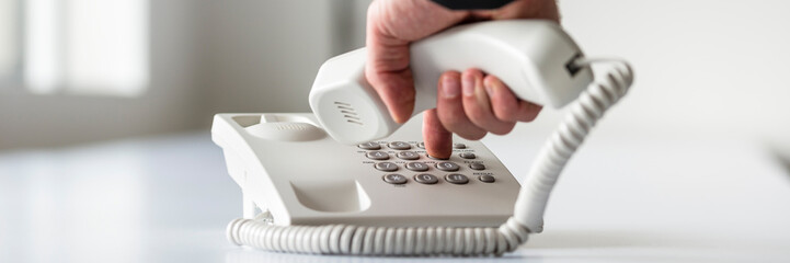 Wide panorama view of a male hand dialing a telephone number