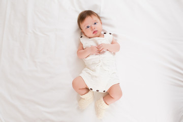 top view of cute adorable baby girl wearing white body in bedroom looking at camera. newborn child r