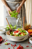 Cooking of seasonal salad with persimmon, pomegranate and dressing from honey and mustard 
