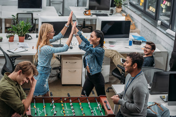 Wall Mural - colleagues celebrating victory in table soccer at modern office