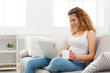© Prostock-studio - Young girl with laptop sitting on beige couch