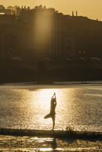 Young Japanese Woman Practicing Yoga Exercises Near A River In A Summer Day In The City At Sunset