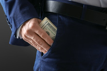 Man In Formal Suit Putting Money In Pocket On Dark Background, Closeup