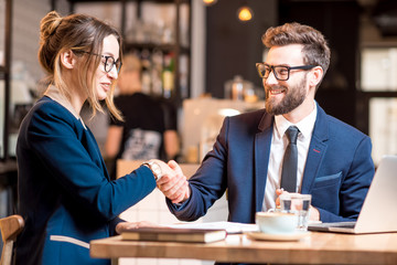 business couple having a deal handshaking together during the lunch at the cafe