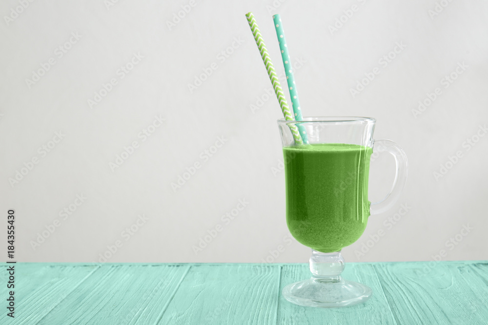 Glass of wheat grass juice on light background