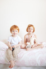 Wall Mural - Red-haired brother and sister are sitting on the bed