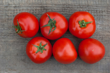 Several juicy red tomatoes on a wooden background.