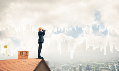 Engineer man standing on roof and looking in binoculars. Mixed m