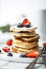 Wall Mural - Pile of american pancakes with strawberries and blueberries before eating.