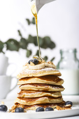 Wall Mural - Pile of pancakes with blueberries on the top, maple leaf syrup pouring on it.