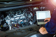 © pikselstock - Mechanic Using Laptop While Examining Car Engine