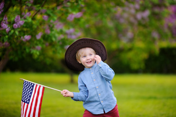 Wall Mural - Cute toddler boy holding american flag in park