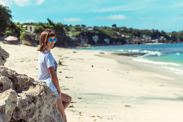 Wall Mural - Beautiful young woman in sunglasses posing on the beach of a tropical island of Bali, Indonesia.