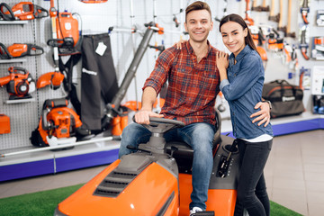 Wall Mural - A young couple is sitting on a lawn mower.