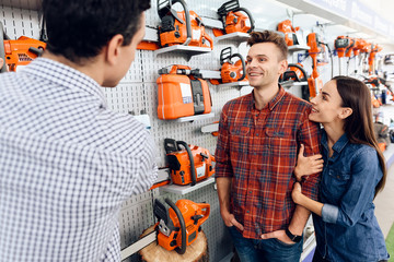 Wall Mural - The seller in the store shows the customers a chainsaw.