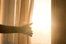 Female Arm Reaching Out To Open A Curtain - Warm Sun Light Shining Through