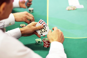 Gambling in cards. Cards in the hands of the player on a green background