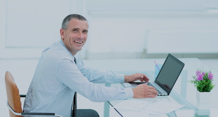 successful smiling businessman working on laptop at Desk in offi