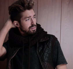 Portrait of young handsome fashionable man against wooden wall.