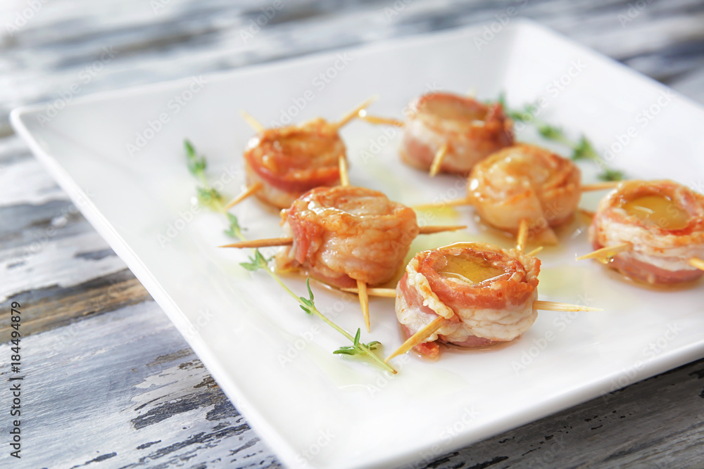 Plate with bacon wrapped scallops on table