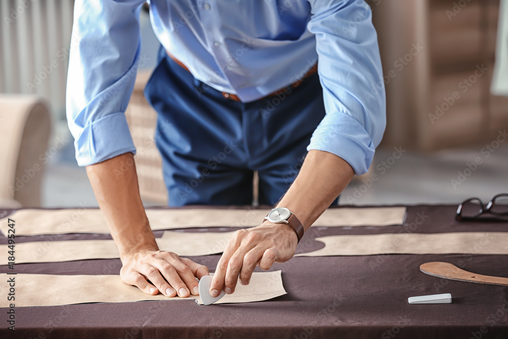 Young tailor working with sewing pattern in atelier