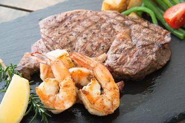 rib eye steak and grilled shrimp on black plate