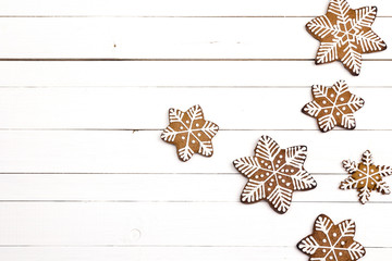 Christmas homemade gingerbread snowflakes on white wooden background.