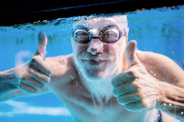 Wall Mural - Senior man swimming in an indoor swimming pool.