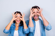 © deagreez - Close up photo of  attractive creative, mad couple making binoculars with their fingers and open mouth standing over grey background