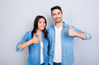 © deagreez - Sweet, attractive, smiling hispanic lovely cute couple in casual outfit showing  thumb up sign over grey background