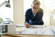 © goodluz - Portrait of architect in office working on blueprints