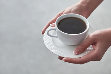 Close-up of a woman's hand holding a cup of hot coffee in office