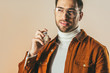 © LIGHTFIELD STUDIOS - portrait of stylish young man applying perfume isolated on beige