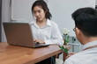 © tuaindeed - Attractive young Asian woman working with laptop with business man giving a white rose in office on valentine's day. Love and romance in workplace concept.